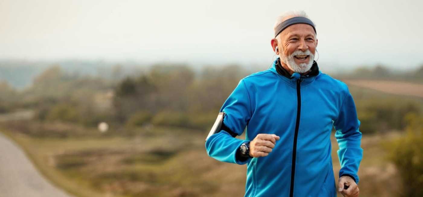 Happy senior sportsman feeling motivated while listening music and running in nature